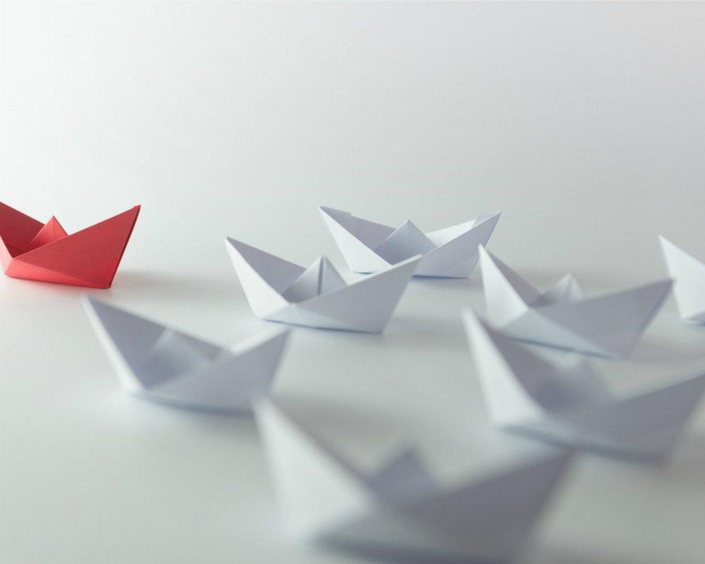 Leadership concept using red paper ship among white