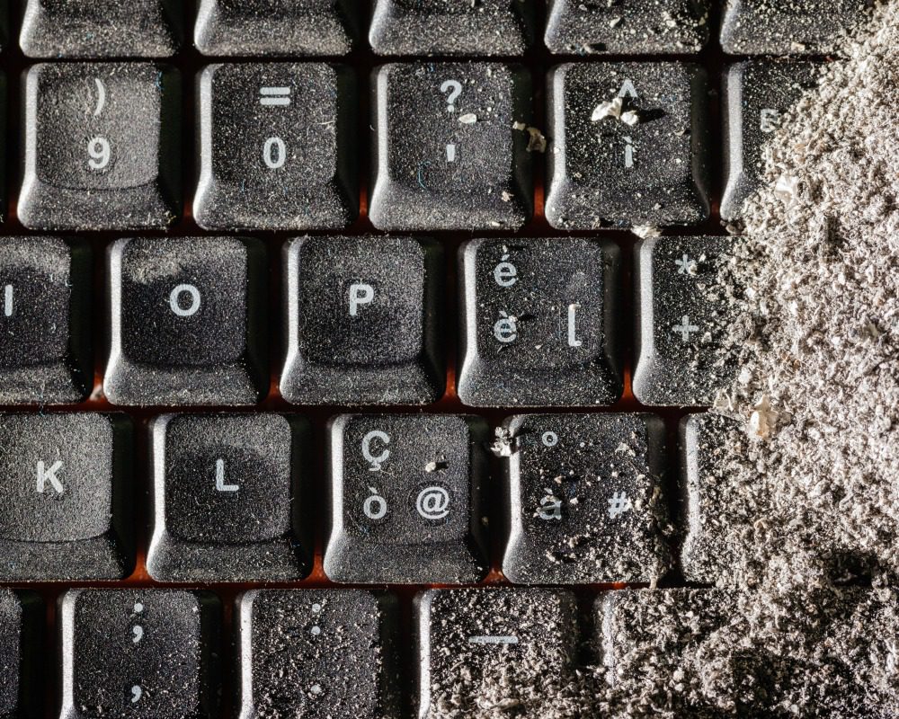 a dirty black keyboard covered in ash or dust