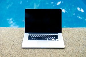 Laptop by the pool, working on vacation with mobility concept