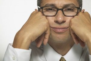 Portrait of a young businessman sitting with his hands on his cheeks