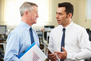 Businessman Having Discussion With Senior Mentor In Office