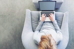 Top down view of young blond person typing on laptop computer